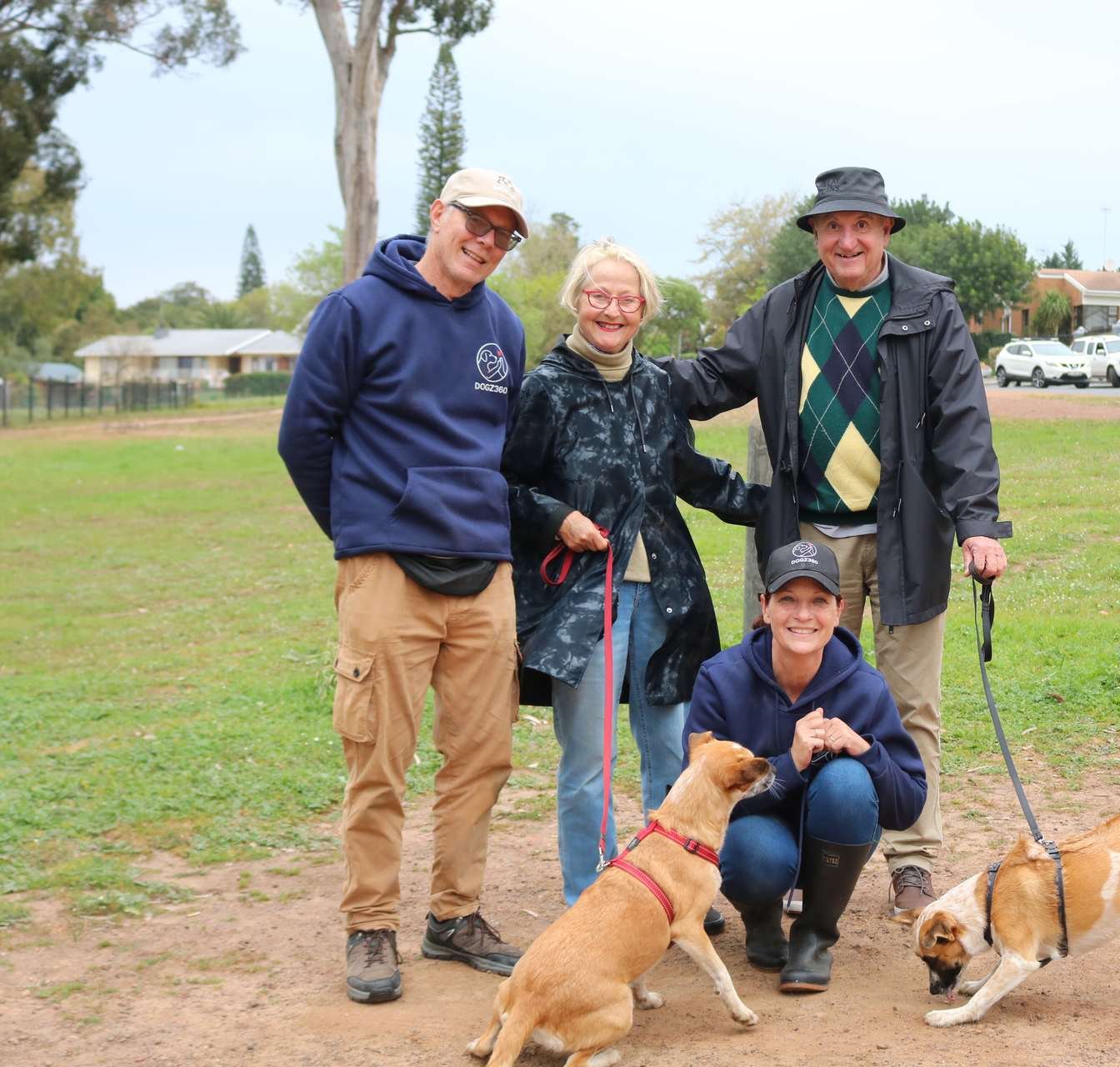 Family group standing with two dogs on a gravel path