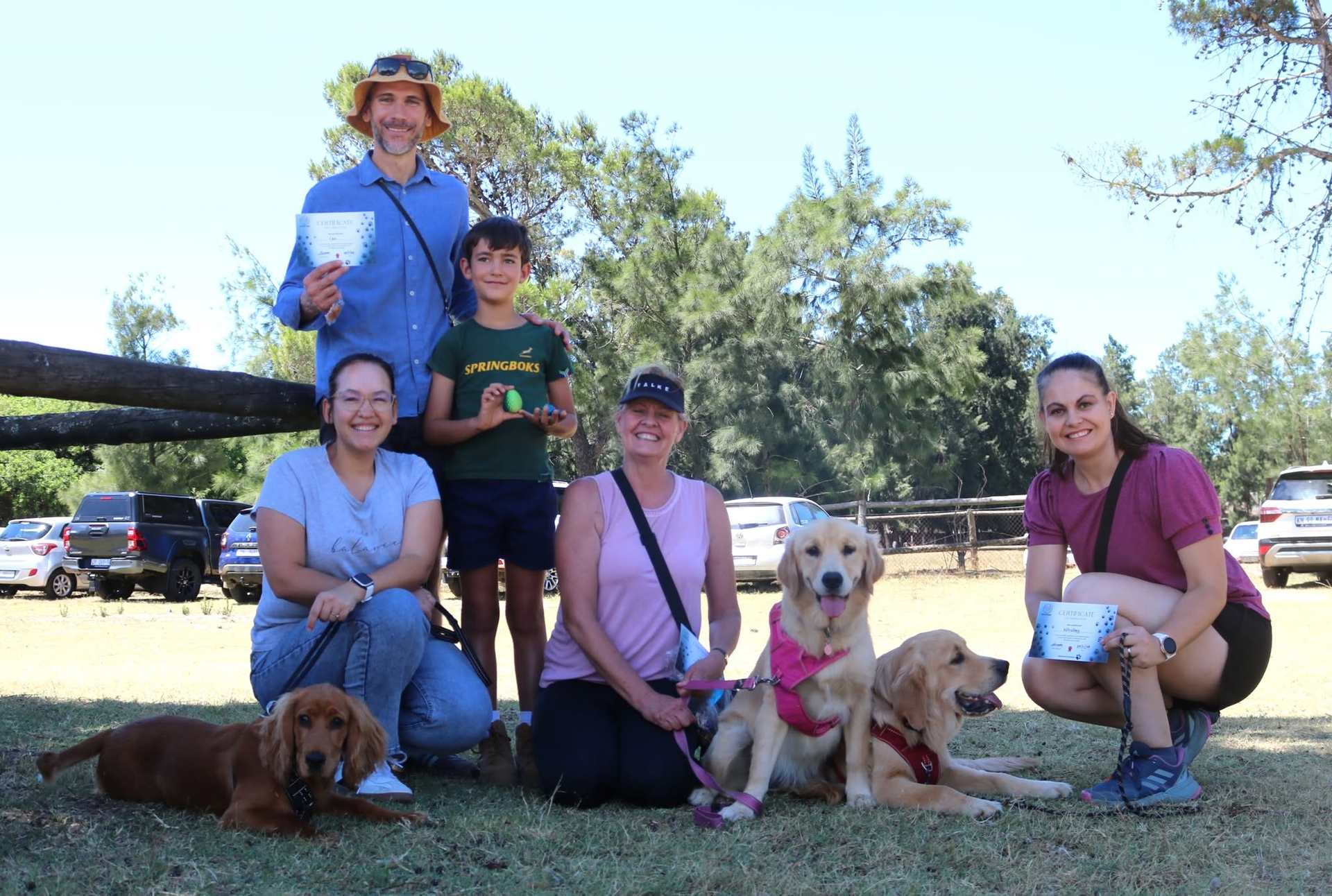 Graduates celebrating with certificates and three happy dogs